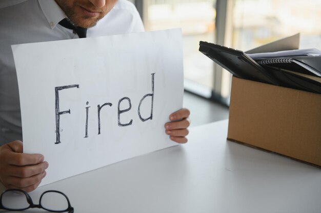 Gefeuerter Mitarbeiter mit gefeuertem Schild in der Hand