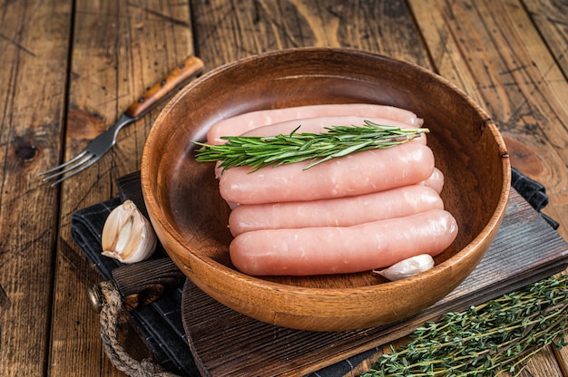 Geflügel rohe Würstchen in einer hölzernen Palette mit Kräutern