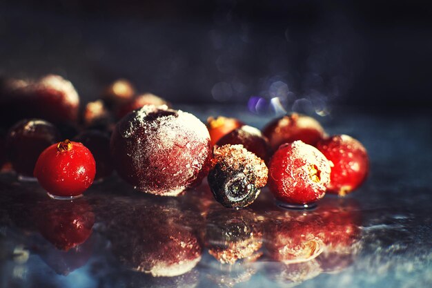 Gefrorene Beeren der Nahaufnahme auf dem Glas mit gefrorenen Beeren der Reflexion auf einem dunklen Hintergrundmakro