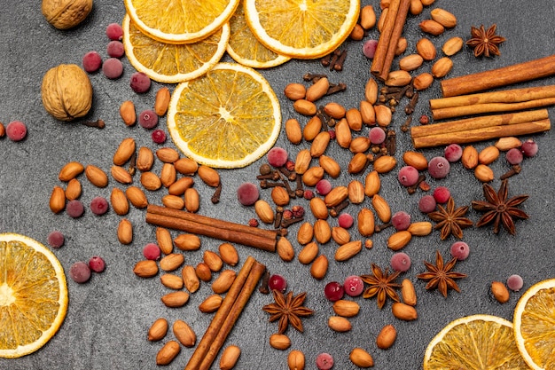 Gefrorene Beeren würzen Nüsse und Orangenchips auf schwarzem Hintergrund