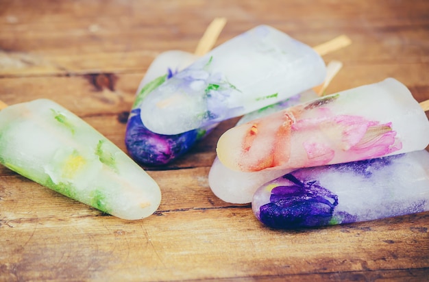 Gefrorene Blumen in Eiswürfeln und Eis am Stiel. selektiver fokus.