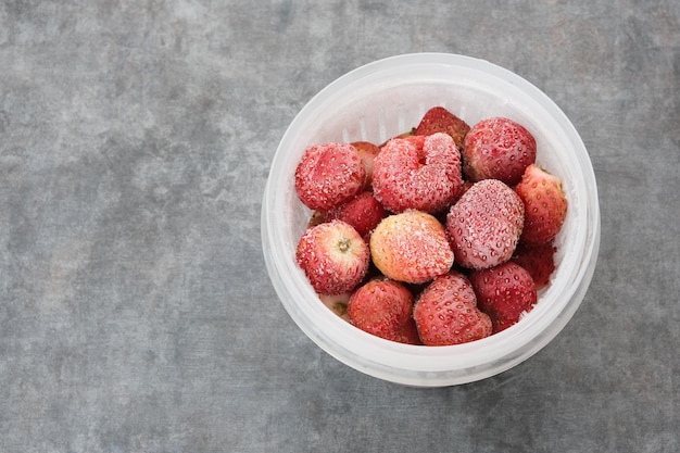 Gefrorene Erdbeeren mit Eiskristallen auf dunklem Hintergrund