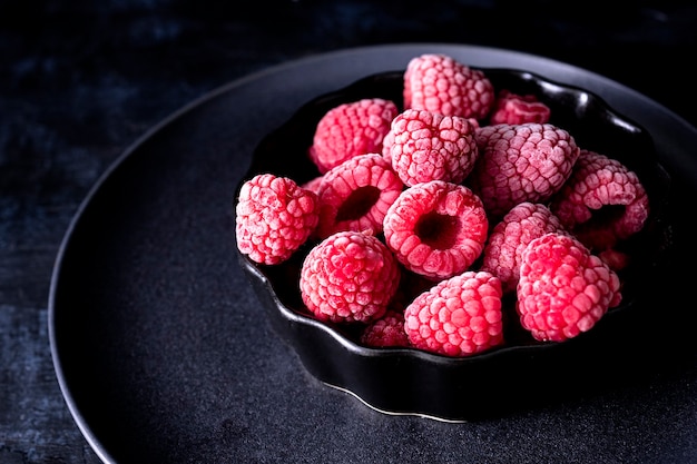 Gefrorene Himbeeren in einer Schüssel und dunklem Hintergrund