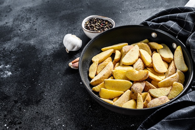 Gefrorene Kartoffelschnitze in einer Pfanne. Pommes frittes. Schwarzer Hintergrund. Draufsicht. Speicherplatz kopieren.