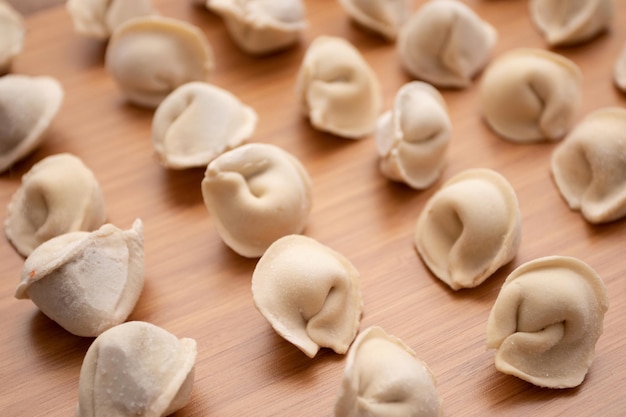 Foto gefrorene knödel-pelmeni auf einem holzbrett.