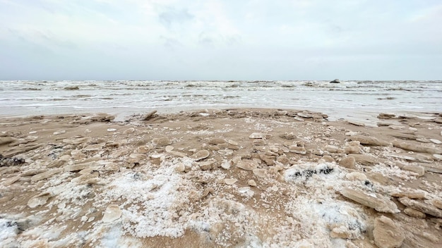 Gefrorene Küste im Winter mit schneebedeckten Dünen. Stimmungsvolle winterliche Meeres- und Strandlandschaft ohne Menschen.