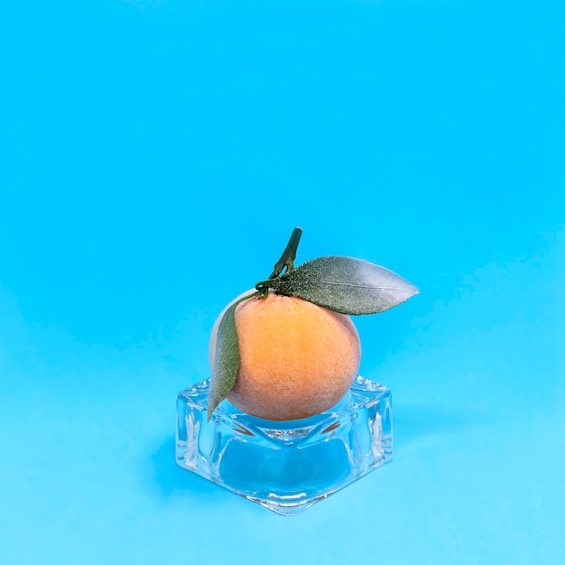 Gefrorene Mandarine auf Eiswürfel auf blauem Hintergrund