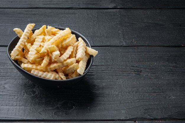 Gefrorene Pommes Frites auf schwarzem Holztisch