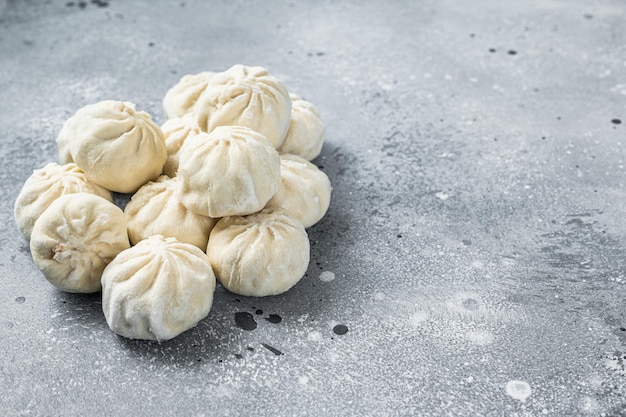 Gefrorene, ungekochte Baozi-Knödel, gefüllt mit Fleisch. Grauer Hintergrund. Ansicht von oben. Platz kopieren.