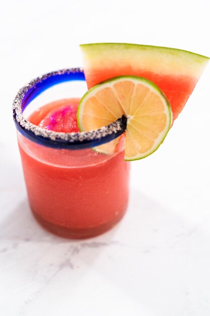 Gefrorene Wassermelonen-Margarita in einem Glas garniert mit Salz, einer Scheibe frischer Wassermelone und Limette.