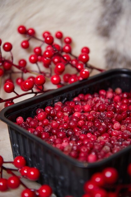 Gefrorene Winterbeeren mit Eis in einer Schüssel auf den Tischzweigen und hinterlässt eine unscharfe Oberfläche