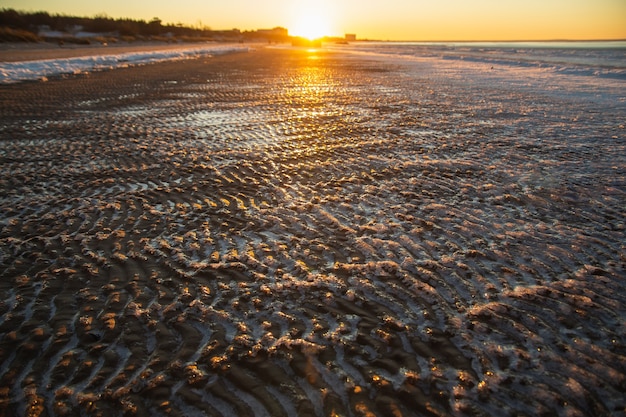 Gefrorener Meeresstrand auf dem Sinset. Eisbedeckte Sandwellen.