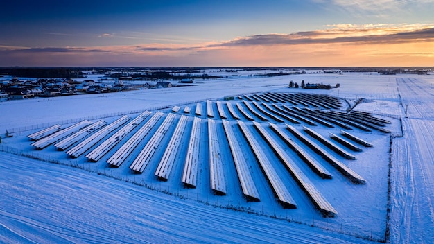 Gefrorener Photovoltaik-Bauernhof im Winter bei Sonnenuntergang Luftbild