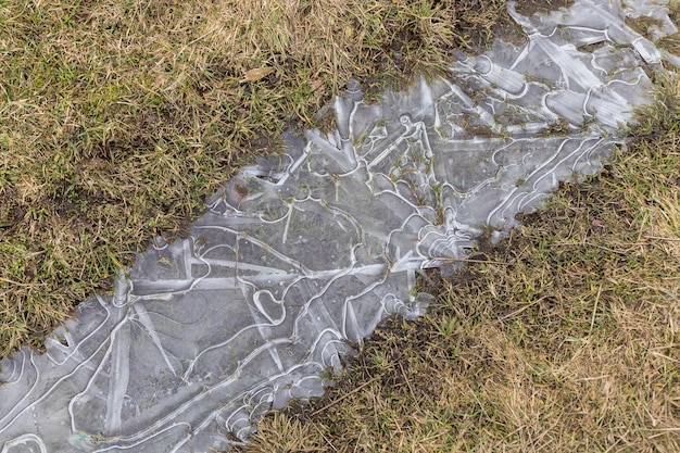 Gefrorenes Eis in einer Pfütze auf einem Feld im Frühjahr