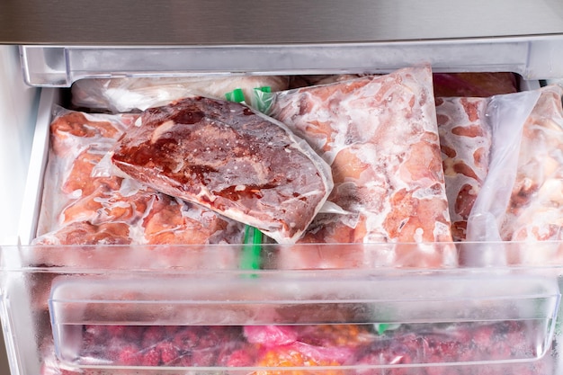 Gefrorenes Fleisch und gefrorene Fleischprodukte in Plastikverpackung im Gefrierschrank. Gefrorenes Essen. Konzept der gesunden Ernährung