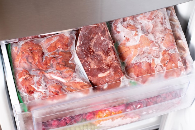 Gefrorenes rohes Fleisch in Plastik verpackt im Gefrierschrank. Konzept der gesunden Ernährung. Gefrorenes Essen