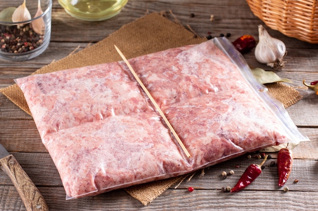 Gefrorenes Schweinehackfleisch auf einem Holztisch. Gefrorenes Essen