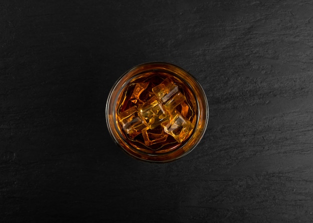 Gefrorenes Whisky-Glas auf natürlichem schwarzem Steinhintergrund