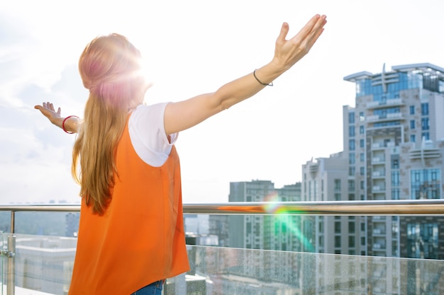 Gefühl der Freiheit. Glückliche nette Frau, die die Sonne beim Stehen auf dem Balkon betrachtet