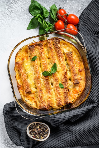 Gefüllte Cannelloni mit Bechamelsauce. Mit Rindfleisch gebackene Nudeln, Sahnesauce, Käse. Grauer Hintergrund. Draufsicht