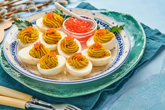 Gefüllte Eier mit rotem Kaviar und Paprika auf Teller für Aperitif-Ostertisch, Draufsicht, Kopierraum. Traditionelles Gericht für Frohe Ostern.