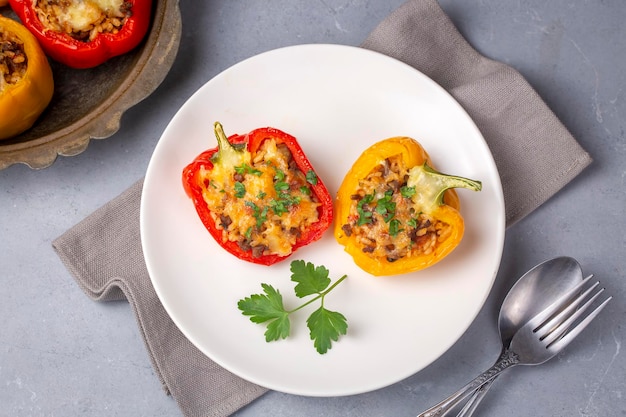 Gefüllte Paprikahälften Paprika gefüllt mit Reis, getrockneten Tomaten, Kräutern und Käse in einer Auflaufform auf einem blauen Holztisch Draufsicht Vegetarisches Gericht gefülltes Gemüse türkischer Name biber dolmasi