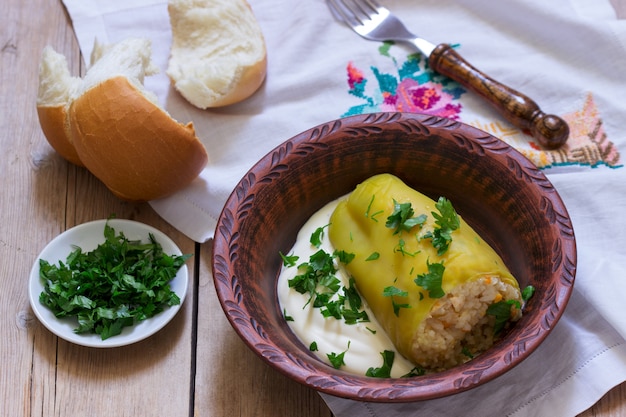 Gefüllte Paprikaschoten, serviert mit saurer Sahne und Brot, einem traditionellen Gericht verschiedener Nationen.