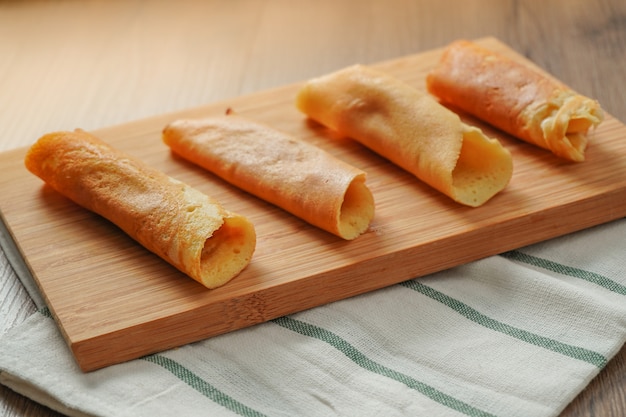 Gefüllte Pfannkuchenrolle verschiedene Aromen auf Bambus Schneidebrett auf weiß und grün gestreiften Stoff auf Holztisch gelegt