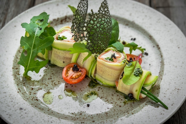 Gefüllte Zucchini mit Frischkäse auf einem weißen Teller gerollt