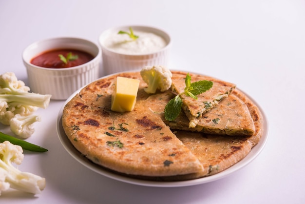 Gefüllter Blumenkohl oder Gobi Paratha ist ein indisches Fladenbrot. Lieblingsfrühstücks- oder Mittagsmenü in Nordindien, serviert auf stimmungsvollem Hintergrund mit Quark und Tomatenketchup in einer Schüssel