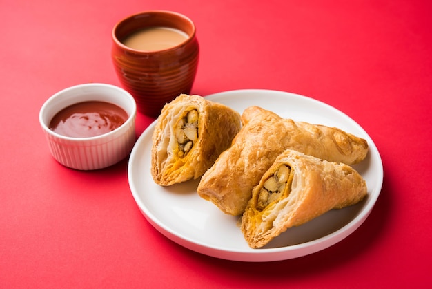 Gefüllter Gemüsepuff oder Samosa, berühmter indischer Bäckereisnack, serviert mit Tomatenketchup und heißem Tee, selektiver Fokus