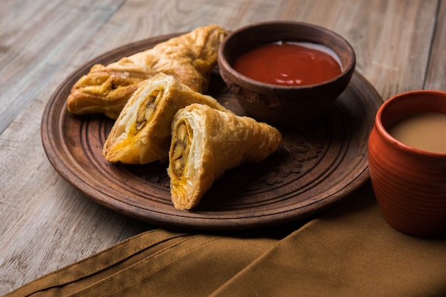 Gefüllter Gemüsepuff oder Samosa, berühmter indischer Bäckereisnack, serviert mit Tomatenketchup und heißem Tee, selektiver Fokus