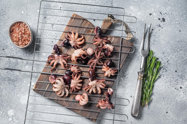 Gegrillte Baby-Mini-Kraken auf einem Grill. Grauer Hintergrund. Ansicht von oben.