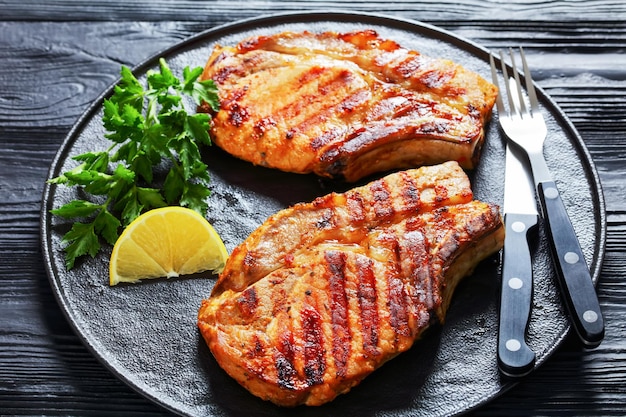 Gegrillte bonein Schweinekoteletts auf einem schwarzen Teller