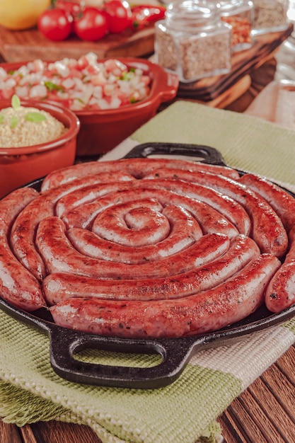 Gegrillte brasilianische Wurst auf Eisenplatte mit Salat, Farofa und Gewürzen