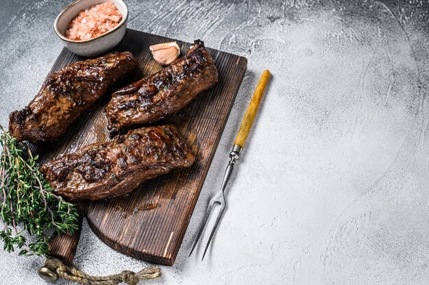 Gegrillte Brisketsteaks in Bbq-Sauce auf einem Holzbrett.