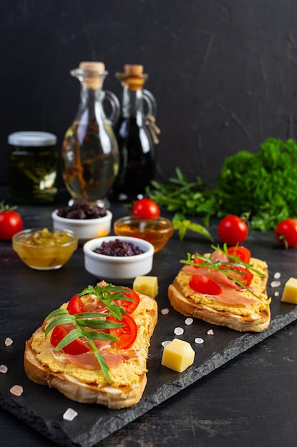 Gegrillte Bruschetta mit Hähnchen-Rillettes, Jamon und Kräutern. Leckerer Toast mit Hühnchenpastete und verschiedenen Vorspeisen