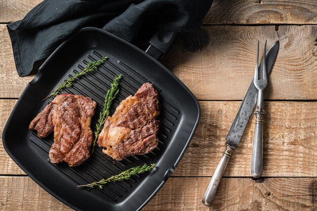 Gegrillte Chuck Eye Roll Rindersteaks mit Kräutern auf Grillpfanne Holzhintergrund Ansicht von oben