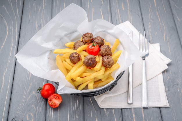 Gegrillte Fleischklöschen mit Pommes-Frites auf hölzernem