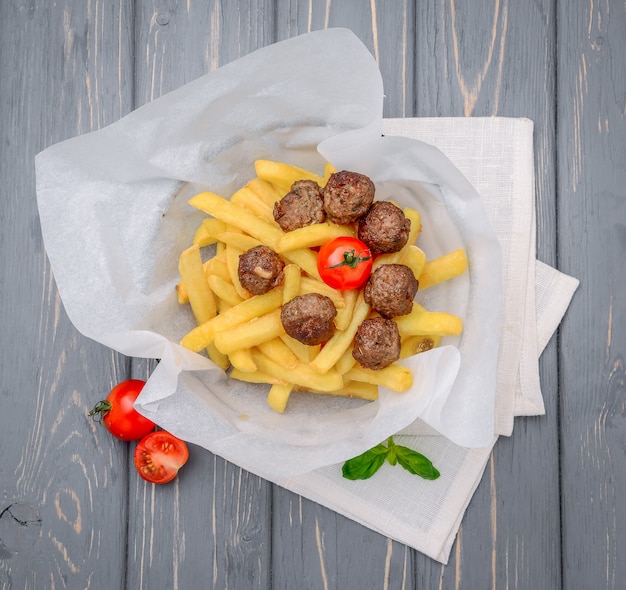 Gegrillte Fleischklöschen mit Pommes-Frites auf hölzernem