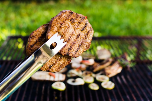 Foto gegrillte fleischpastetchen in der zange draußen auf picknick