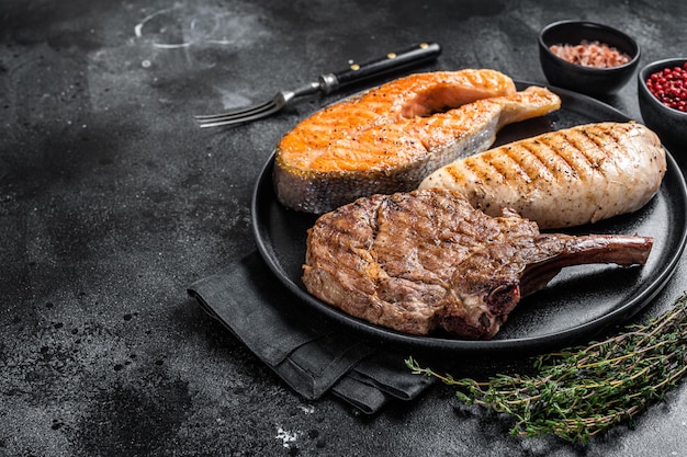 Gegrillte Fleischsteaks - Fisch-Lachs, Rind-Kalb und Putenfilet. Schwarzer Hintergrund. Ansicht von oben. Platz kopieren.