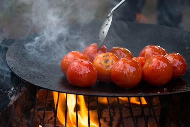 Gegrillte geröstete Tomaten auf einer heißen Pfanne am offenen Feuer