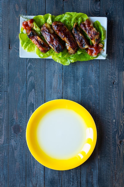 Gegrillte Grillschweinefleischrippen mit Gemüse auf einem hölzernen Hintergrund;