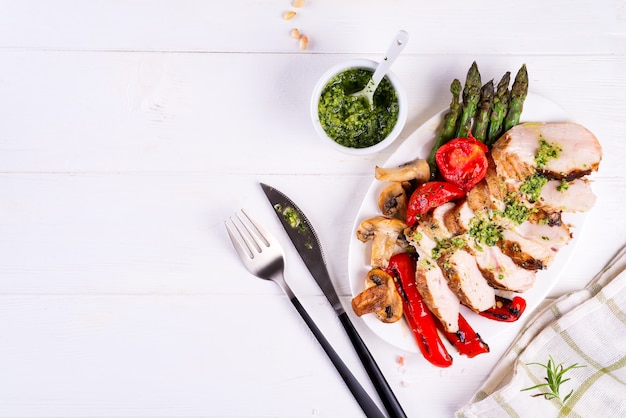 Gegrillte Hähnchenbrust auf einem Teller mit Tomaten, Spargel und Champignons auf einem Teller, flach legen