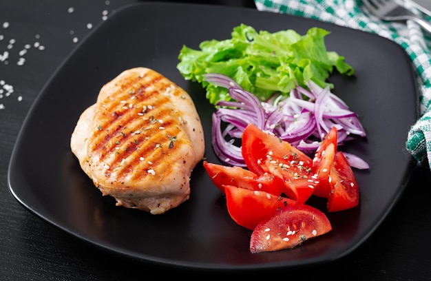 Gegrillte hähnchenbrust gebratenes hähnchenfilet und frisches gemüse salat aus tomaten, roten zwiebeln und salat hähnchenfleisch mit salat