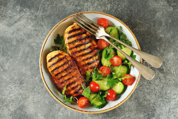 Gegrillte Hähnchenbrust mit einem Salat aus Kirschtomaten, Gurken, Rucola und Petersilie