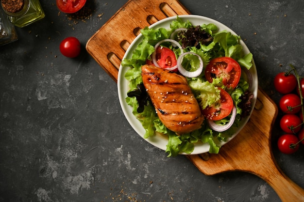 Gegrillte Hähnchenbrust mit frischem Salatgemüse auf grauem Hintergrund