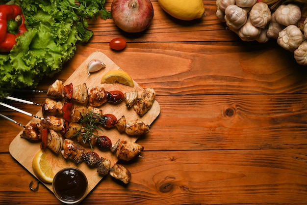 Gegrillte Hähnchenfleischspieße mit Cherry-Tomaten-Paprika und Zwiebeln auf rustikalem Holztisch Konzept der Grillparty