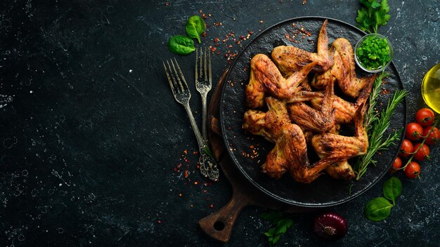 Gegrillte Hähnchenflügel mit Sauce und Gewürzen auf einer schwarzen Steinplatte Draufsicht Freier Platz für Text